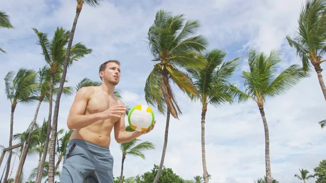 Beach volleyball serve - man serving in beach volley ball game on beautiful summer day. Young people having fun in the sun living healthy active sports lifestyle outdoors. Underhand serve. RED EPIC.