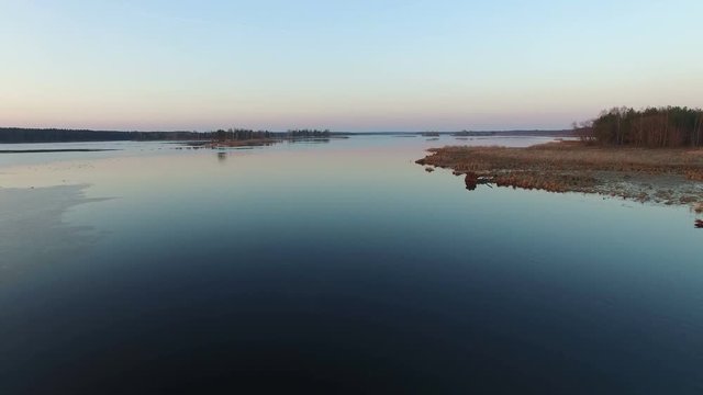 4K. Low flight and takeoff over wild lake with ducks in early spring on sunset, aerial view.