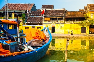 Fototapeta na wymiar Traditional boats in front of ancient architecture in Hoi An, Vietnam. Hoi An is the World's Cultural heritage site, famous for mixed cultures & architecture.