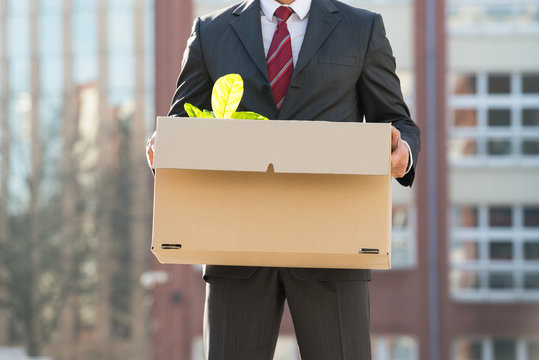 Close-up Of Businessperson Standing With Cardboard Box Outside O