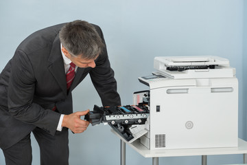 Businessman Fixing Cartridge In Printer Machine At Office