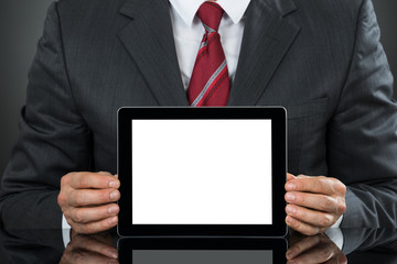 Businessman Showing Tablet With Blank Screen At Desk