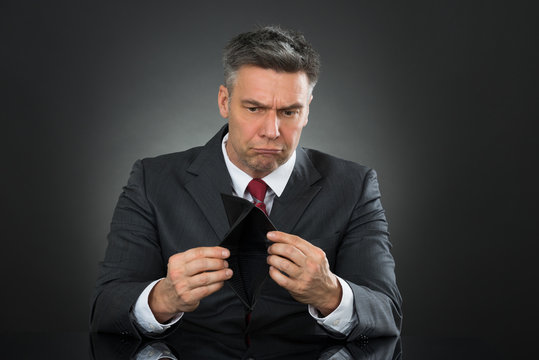 Businessman With Empty Wallet Sitting At Desk