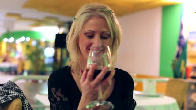 Smiling drunk woman laughing and tasting wine in a restaurant. blurred backgound