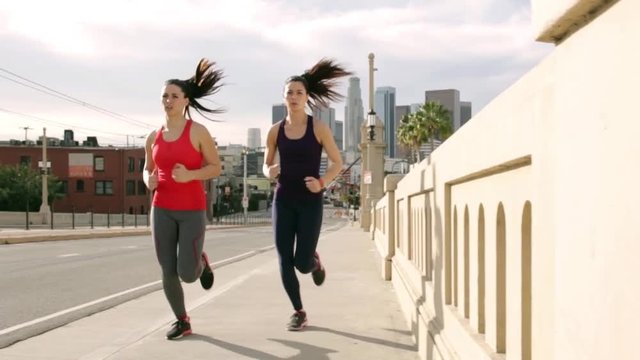Group of women train running with endurance in urban street downtown industrial city skyline