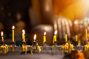 Yellow candles with Blur Buddha statue on background. Thailand travel and religion concept.
