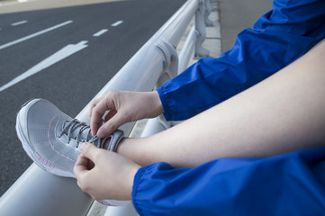 Female runner has signed a shoelace over the legs to the guardrail