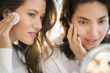 Women looking in mirror and applying facial cream