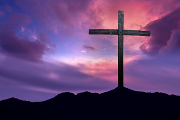 Christian cross over dark sunset background