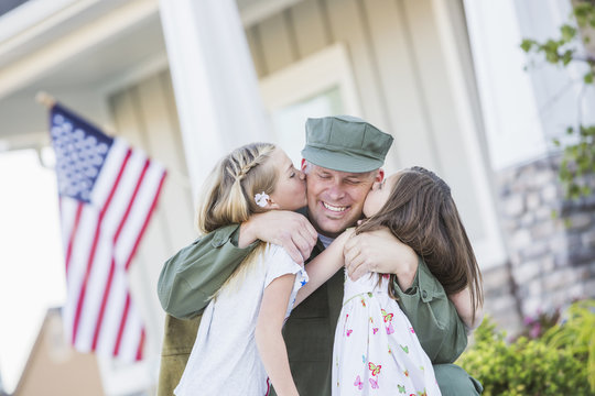 Returning soldier hugging daughters