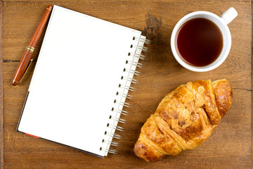 croissant cup coffee white book pen  on teak wood