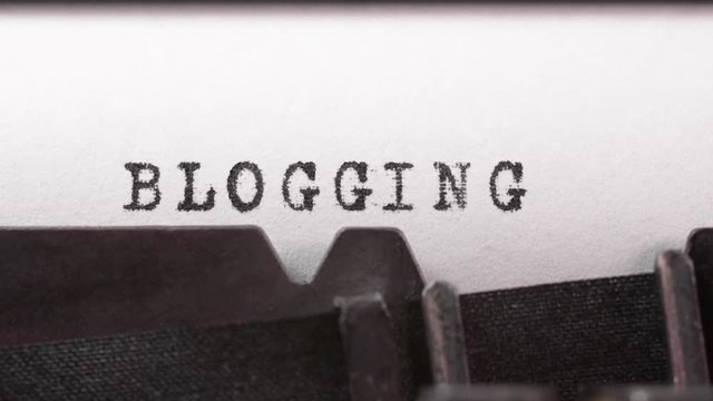 Typing the word Blogging on an old manual typewriter. The action of writing a blog.