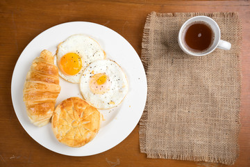 breakfast biscuit croissant egg coffee on teak