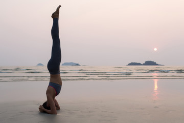 Fototapeta na wymiar Young slim woman practicing pose from yoga on the beach at sunse