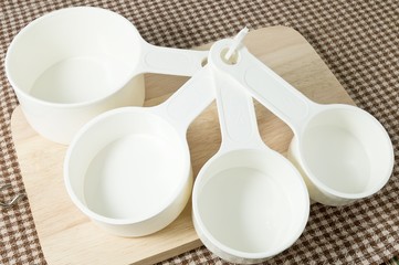 Four Plastic Measuring Cups on Wooden Board