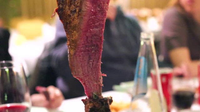 Closeup of a Picanha meat cutting on the blade in  Brazilian Steakhouse Restaurant