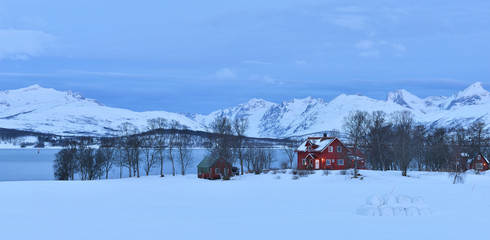 Red farmhouses in Tromso with the mountains on Kvaloya