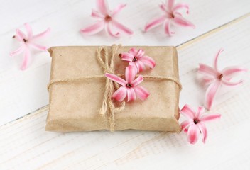 Simple cute gift box decor. Wrapped in parchment paper, delicate fresh pink flowers. Shallow DOF, soft focus.