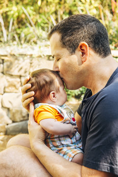 Caucasian father kissing baby boy outdoors