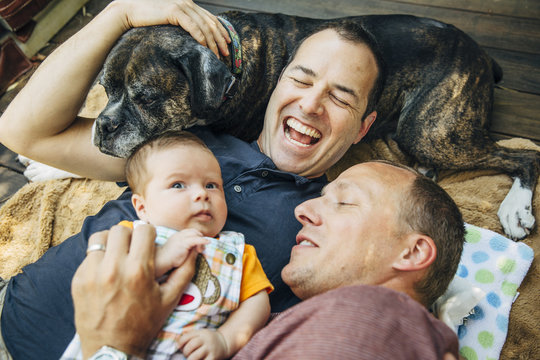 Couple lying on rug with their baby and dog