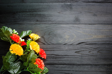 Fototapeta premium colorful Plastic flowers on black wooden table