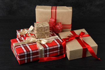 beautiful gifts wrapped with festive ribbon on a black wooden background