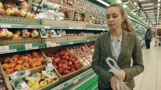 Woman selecting red peppers in modern supermarket