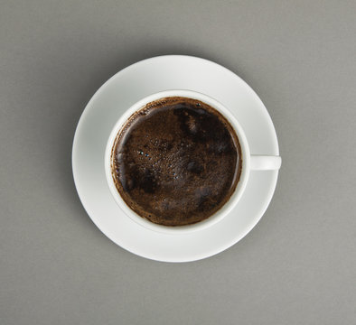 Cup of coffee and saucer on a gray background