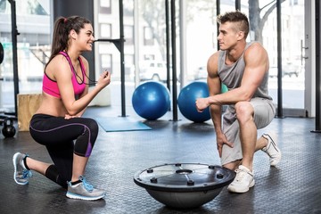 Obraz premium Athletic man working out helped by trainer woman