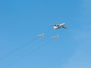 Ilyushin Il-78 (Midas) four-engined aerial tanker demonstrates refueling of 2 Sukhoi Su-24 (Fencer) supersonic all-weather attack aircrafts on blue sky background
