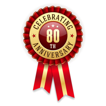 Gold 80th anniversary badge, rosette with red ribbon on white background