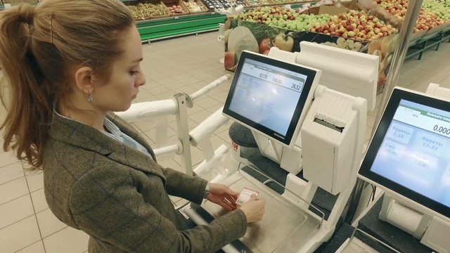Woman buying and weighing lemon in modern supermarket