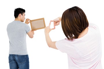 Young couple putting up picture frame