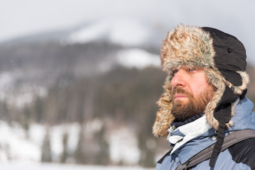 Fototapeta premium Bearded man wearing hat with ear flaps in cold day