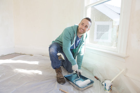 Mixed race man painting walls of home