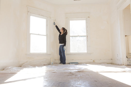 Mixed race woman painting walls of new home