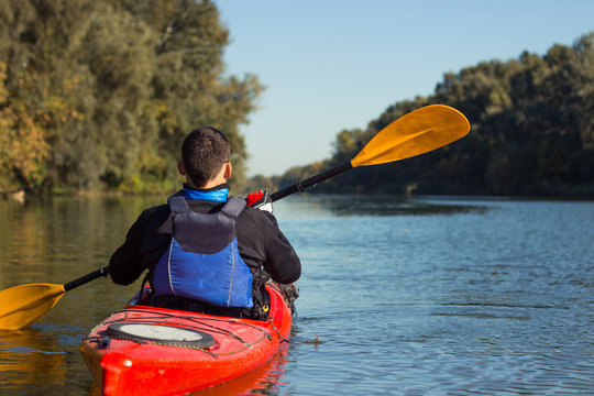 The man is kayaking on the river. 
