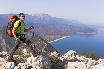 Young man with backpack on a mountain top on a sunny day.