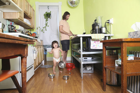 Girl playing in kitchen as father cooks