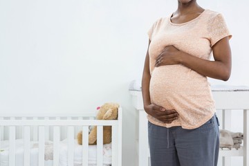 Pregnant woman standing near cradle 