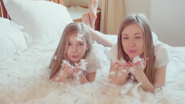 Cute happy girls playing with fluff and feathers. Slowmotion