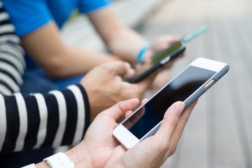 Group of people using cellphone together and sitting at outdoor