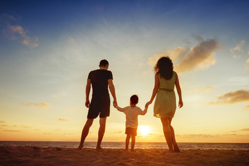 Family of three person is standing on sunset and sea backdrop