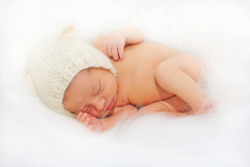 Sleeping happy newborn baby in white fur