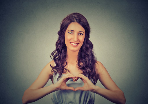 smiling cheerful happy young woman making heart sign with hands
