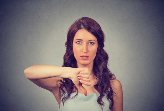 Unhappy woman giving thumbs down gesture looking with negative expression and disapproval