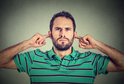 headshot displeased young man plugging ears with fingers doesn't want to listen