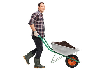 Gardener pushing a wheelbarrow full of dirt
