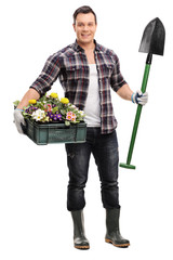 Gardener holding a shovel and crate with flowers