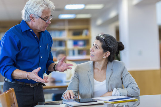Teacher helping adult student in library